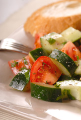 A tomato cucumber salad with vinegrette and bread