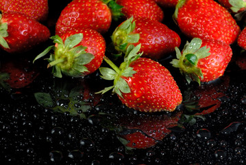 Fresh strawberries with water drops on wet black surface