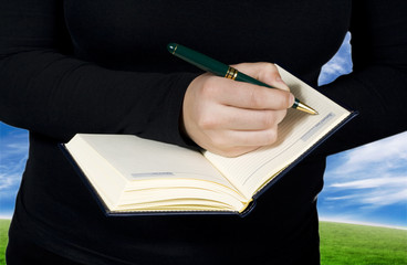 Close-up of a hand starting to write in a blank notebook