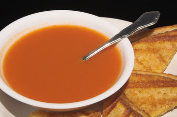 A grilled cheese sandwich and a bowl of tomato soup.