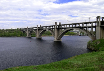 Fototapeta premium Arch bridge on a dark river with green banks