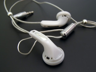 White earphones with cable against the black background