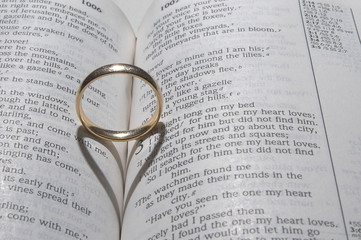 A wedding ring on a bible open to marriage scripture.