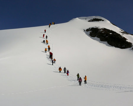 a parade of colorful jackets heading up a hill in antarctica