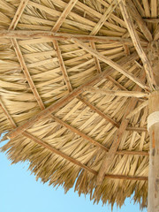 looking up at the inside of a wooden beach umbrella 
