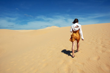 a girl walking in sand dunes