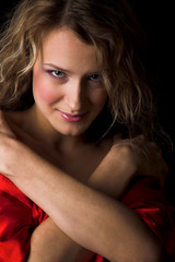 Young woman in red silk isolated in the black background