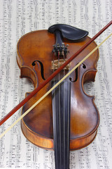 Fototapeta premium Alte Violine mit Bogen mit Noten im Hintergrund