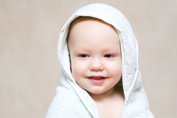 Little happy baby under light blue towel after bath