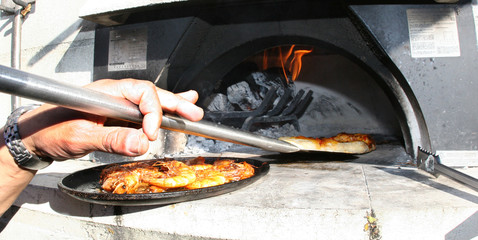 Fototapeta na wymiar Making Pizza in a Wood Burning Oven
