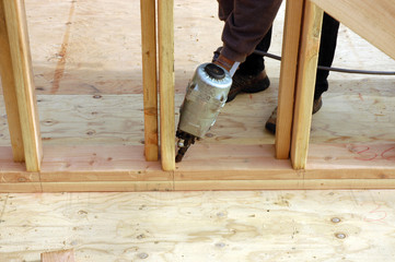 hispanic carpenter nailing the bottom plate 