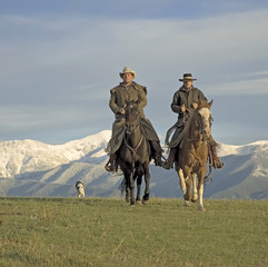 Cowboys on the range, mountain backdrop. 