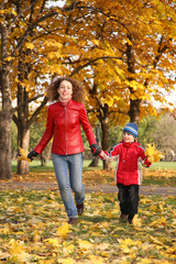 Fototapeta premium mother goes for a walk with the son in the park in autumn