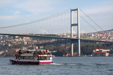 Iústanbul Bosphorus Bridge with ferries at coast side.