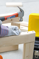 man with safety gloves holding screw and hammer