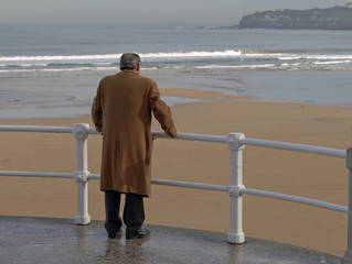 Hombre con abrigo mirando al mar