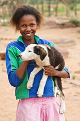 African girl with a puppy, rural area near Kalahari desert