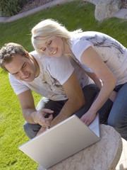 Attractive young couple outdoors with computer