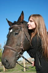Fototapeta premium Long-haired female model with black horse close-up portrait