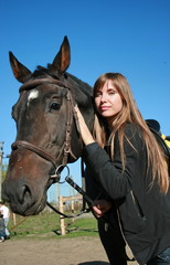 Obraz premium Long-haired female model with black horse close-up portrait