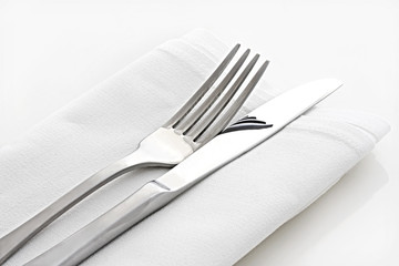 Silver knife and fork on white linen napkin. © robynmac