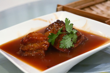Pork stew garnished with chinese parsley on a white serving dish