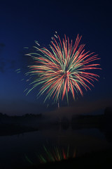 Fireworks display in front of a lake.