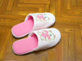 Childlike slippers on parquet, bear with heart