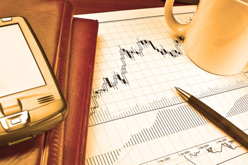 PDA and notebooks on Forex candlestick chart in yellow lighting