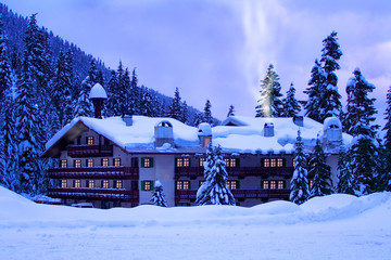 A mountain hotel covered by deep snow with glowing windows.