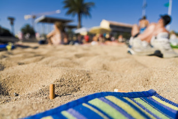 Fototapeta na wymiar niedopałek w piasku na plaży zanieczyszczenia