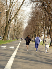 Three men jogging along asphalt alley