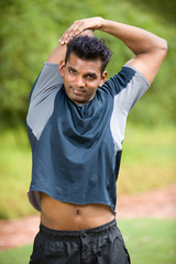 A young Asian man in sportswear stretching outside