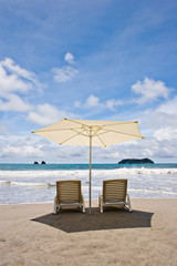 Two chairs and umbrella at the beach.