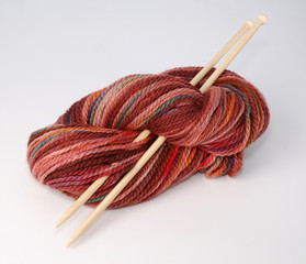Red hank of knitting yarn and bamboo needles