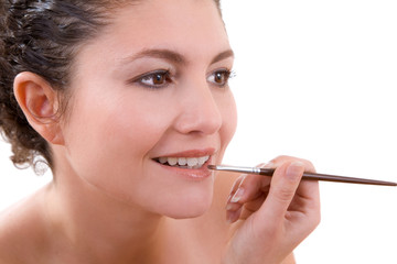 Pretty brunette applying lipgloss to her lips