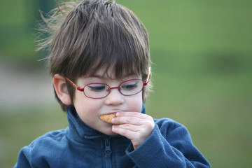 petit garçon avec des lunettes entrain de manger un gâteau