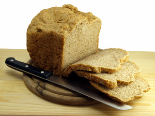 Sliced home-made wholemeal bread on board with bread knife