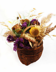 Dry flowers in the small basket arranging on the white 