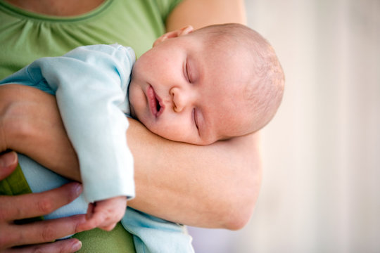 Newborn baby sleeping on her mothers arms