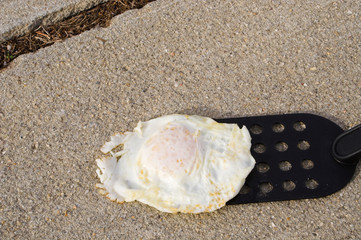 Concept of a hot day. Frying an egg on the sidewalk.