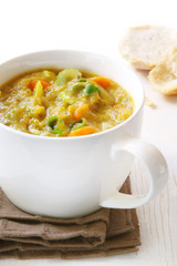 Chunky vegetable soup in white soup cup.