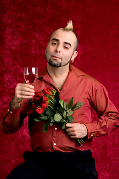 A young man with a dozen red roses and a glass of wine.