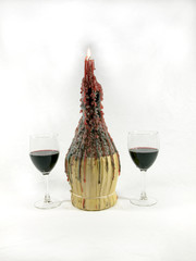 Photo of 2 glasses of wine nest to a wine bottle candle holder