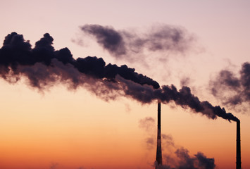 Air polluting smokestack against sunset sky