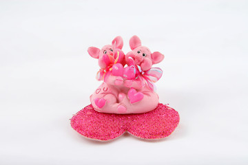 two pink pigs sitting on heart and holding heart
