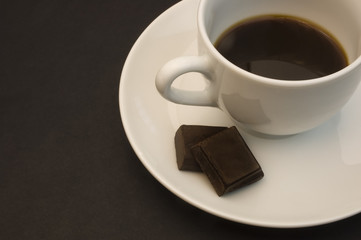 Coffee cup detail with two chunks of chocolate