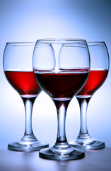Still-life with three glasses of red wine over blue background