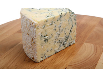 A wedge of mature Stilton cheese on a wooden board