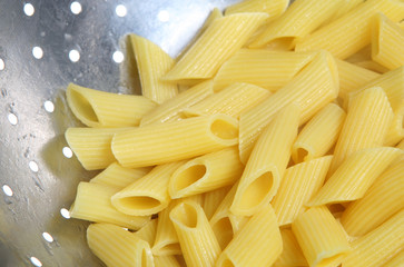Close-up of penne pasta draining in colander
